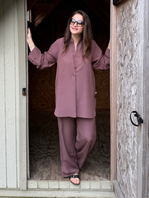 Woman in a mauve outfit standing in a doorway.
